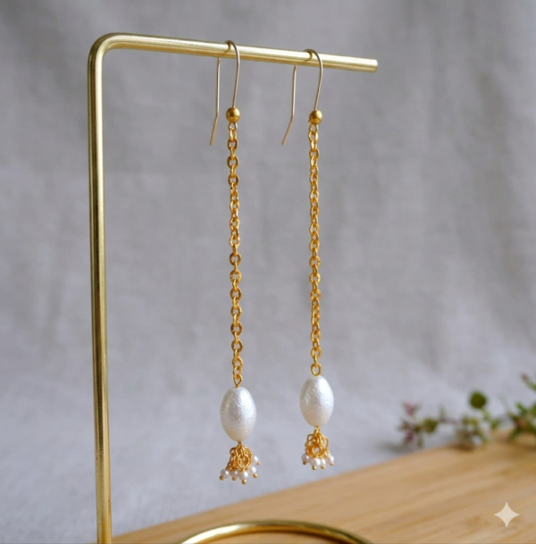 Jewelry product photography of long gold and pearl earrings.