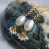 Detailed view of gold chain earrings with pearl and cluster bead charms.