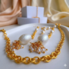 Close-up of gold statement earrings with pearl drops on a white marble background.