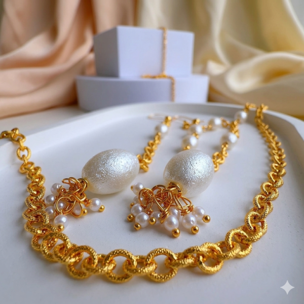 Close-up of gold statement earrings with pearl drops on a white marble background.
