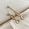 Elegant asymmetric pearl drop earrings in 18k gold plating, highlighting the contrast between the long bar and the short oval link.