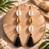 Close-up of anti tarnish jewelry featuring gold and white shells with black tassel clusters.