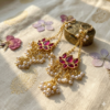 Handcrafted Jalja gold-plated dangles featuring vibrant purple stone settings framed by dangling pearl clusters.